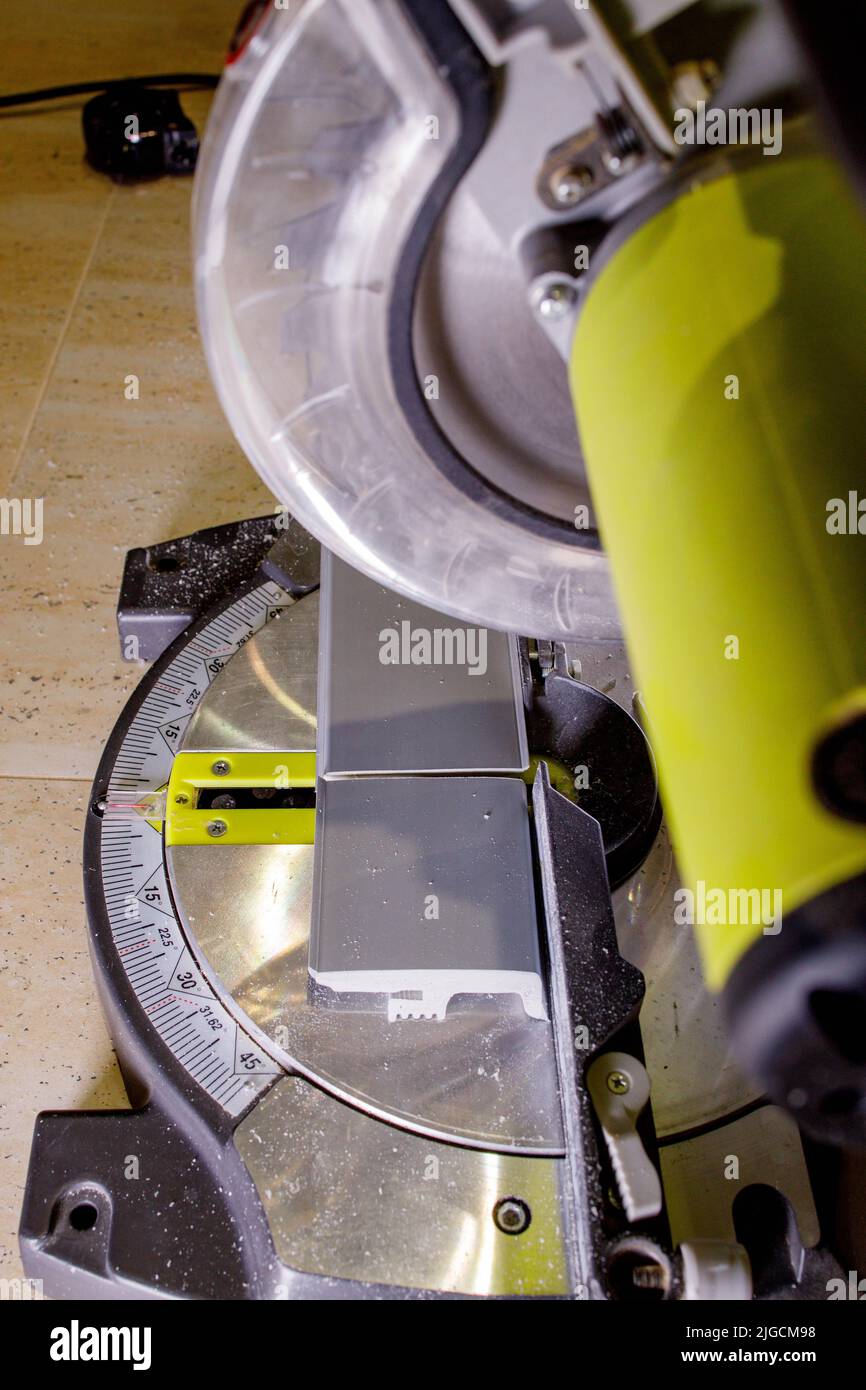 Worker cutting baseboard on the circular saw before installing Stock
