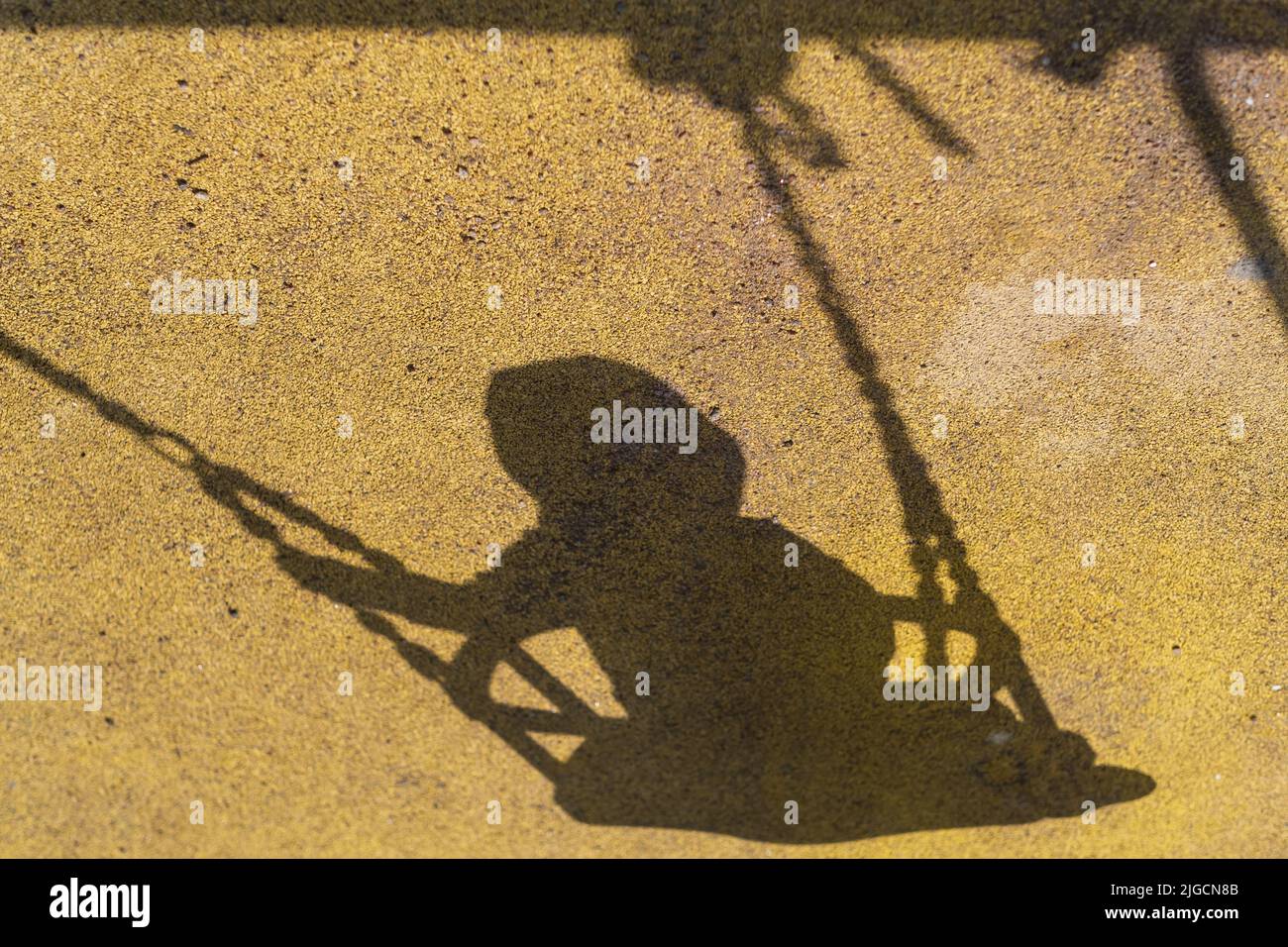 Shadow of baby girl in swing. Playing on playground. Stock Photo