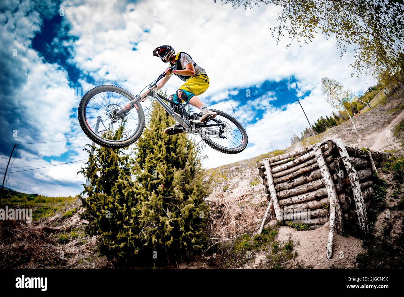 A male rider in a helmet on a bike doing an extreme jump over a track
