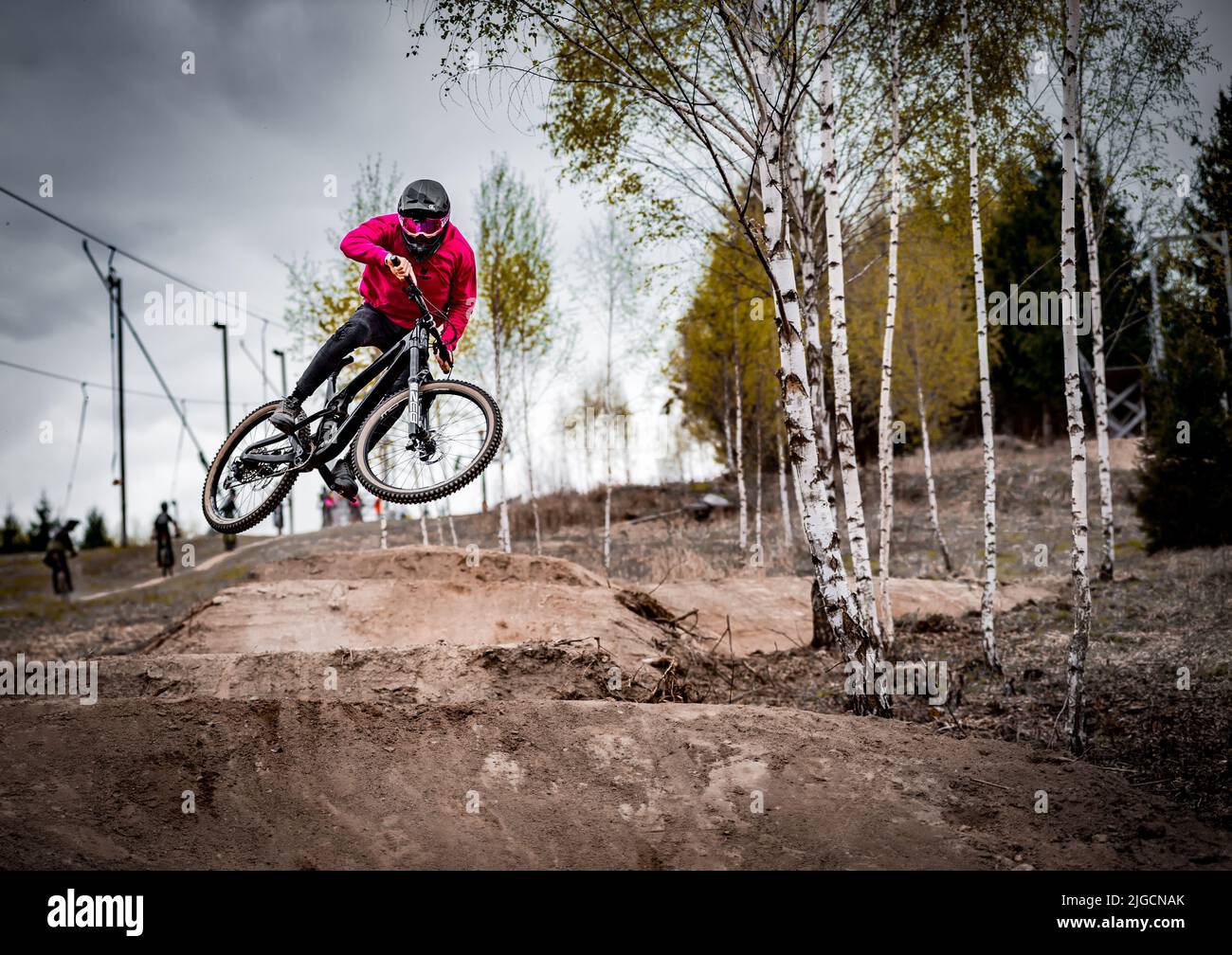 A male rider in a helmet on a bike jumping over a track at a bike park