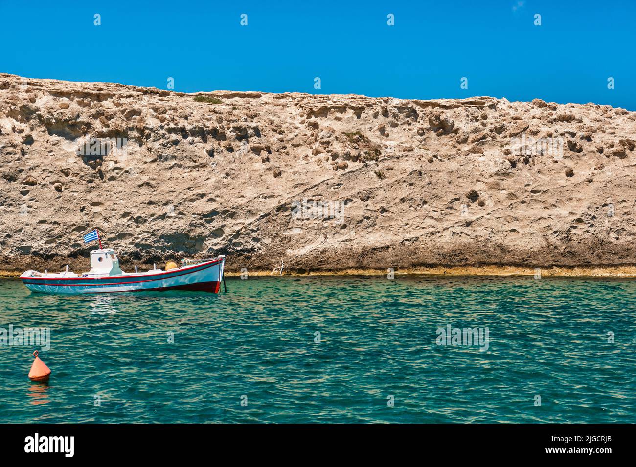 Anchored small fishing boat under Greek flag, azure sea waters, clear ...
