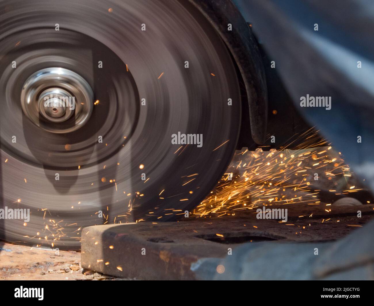 A grinder is grinding quickly and sparks are flying around Stock Photo