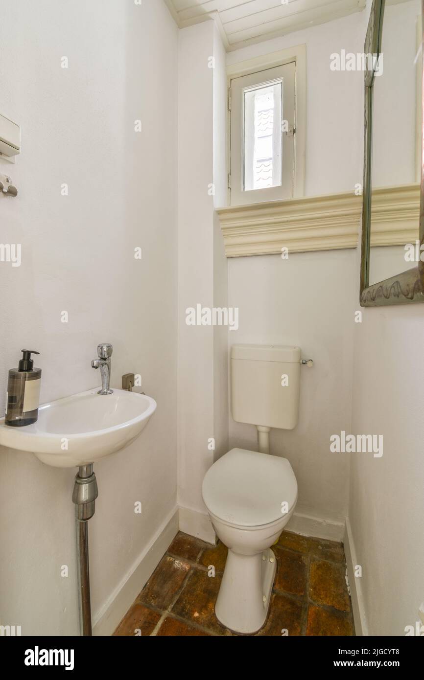 Wall hung toilet and small sink in corner in lavatory room with beige