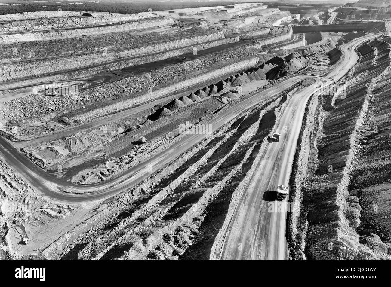 Deep excavated open pit black coal iron ore mine in NSW of Australia Hunter valley - aerial view of trucks and excavators. Stock Photo