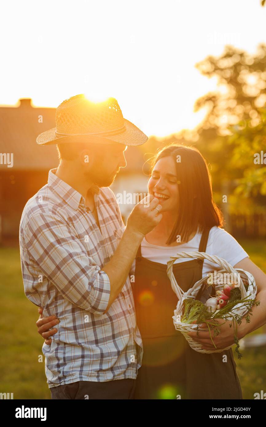 Portrait of young happy farmer couple holding basket with fresh organic ...