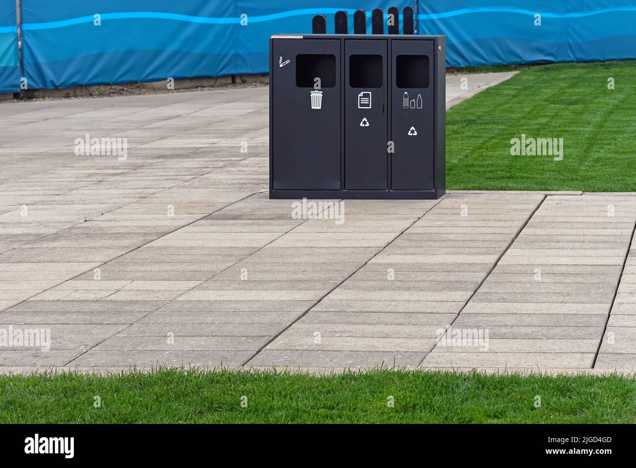 Black recycling bin with three sorting compartments in urban park Stock