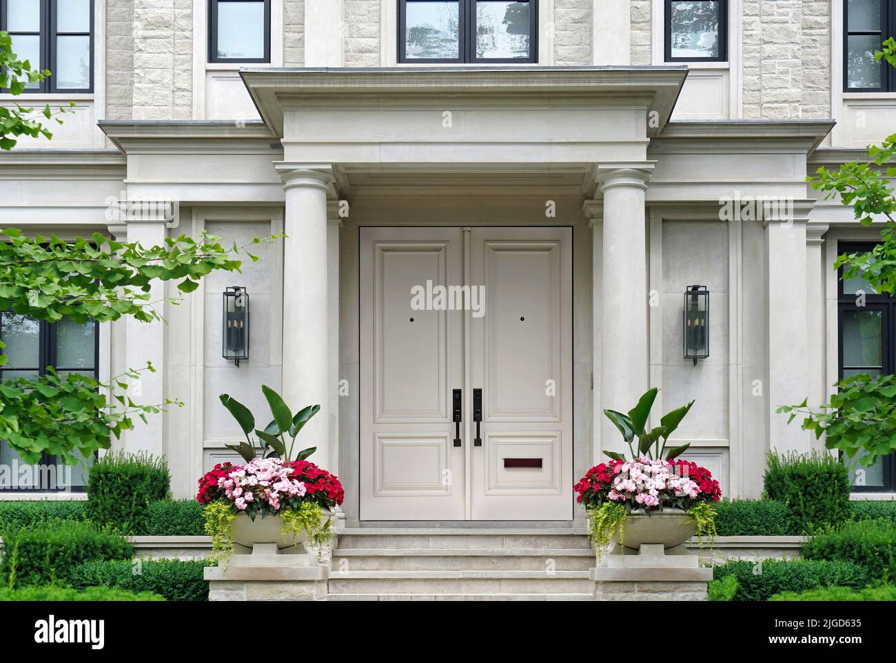 House entrance with columns surrounded by pots of flowers Stock Photo