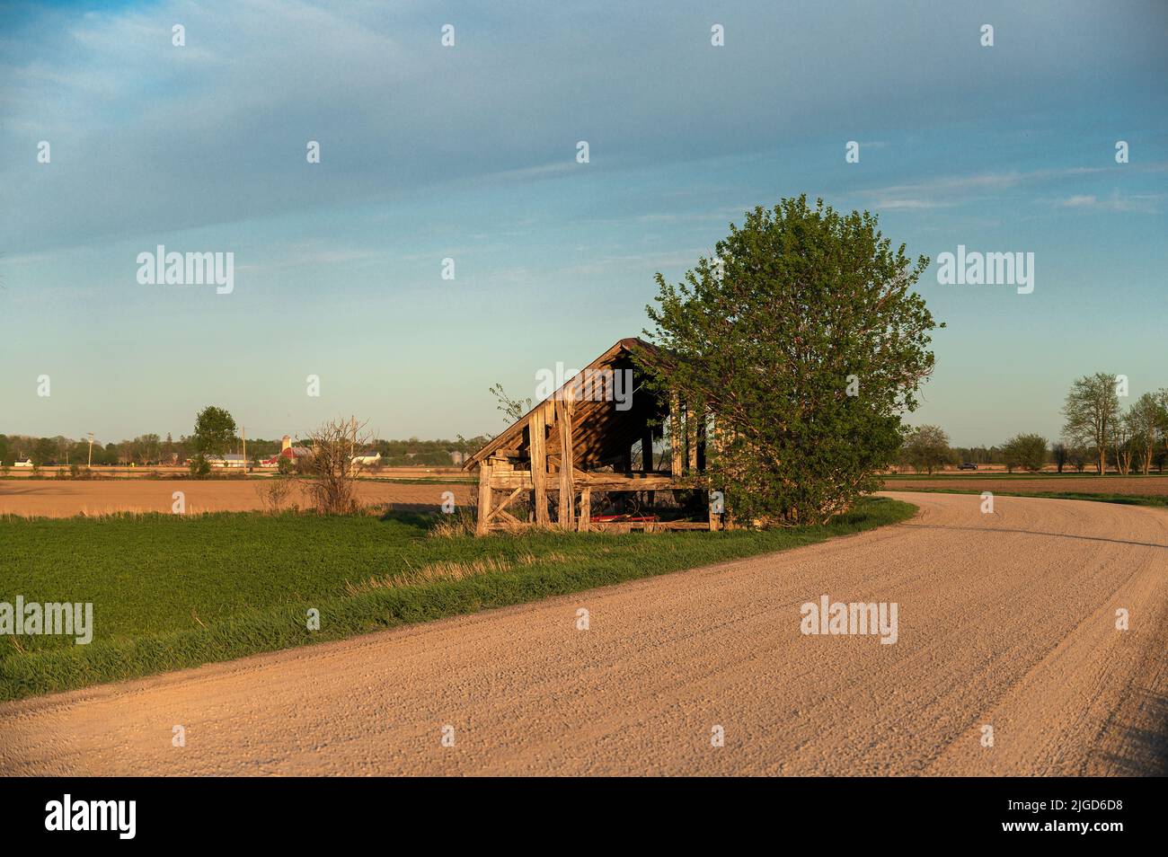 Abandoned farm building by gravel road Stock Photo