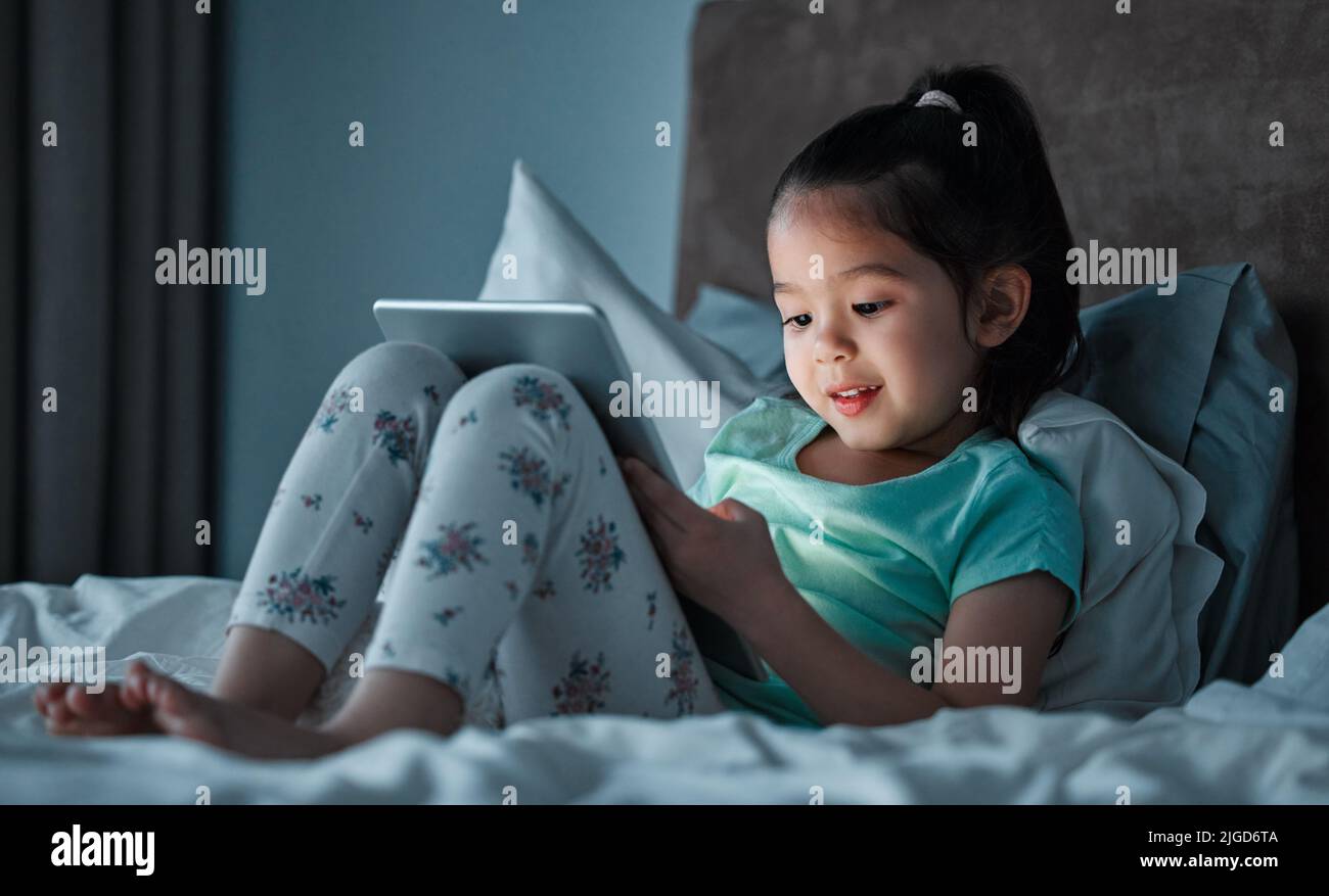 I get a few minutes of screen time before bedtime. a little girl using a digital tablet while