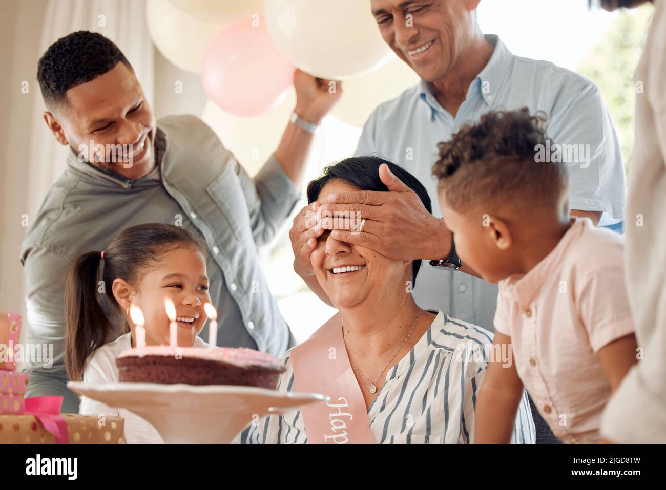 Can I open my eyes yet. a family surprising their mother with a birthday cake at home. Stock Photo