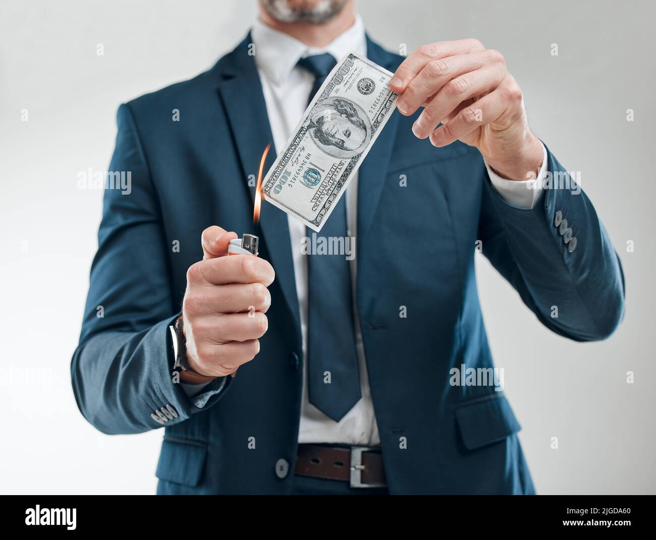 He sure has money to waste. Studio shot of an unrecognisable businessman burning a banknote against a white background. Stock Photo