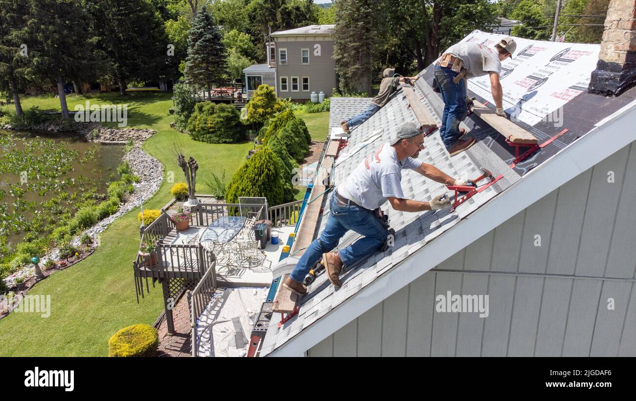 Roofers retiling the roof of a home in Athens, Greene County, New York, USA Stock Photo