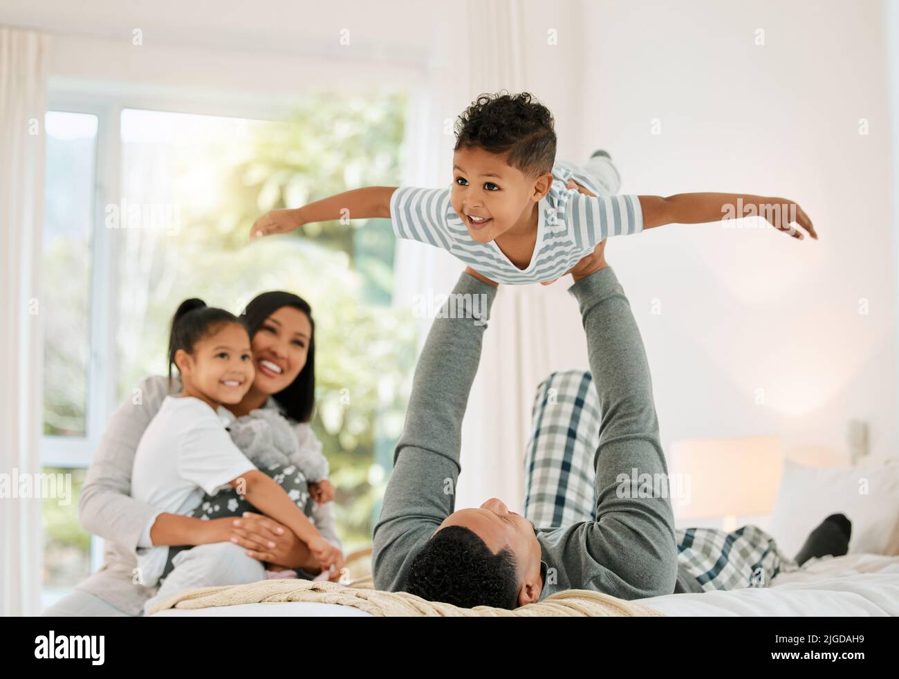 Daddy gave me WINGS. a young family playing together in a bed at home. Stock Photo