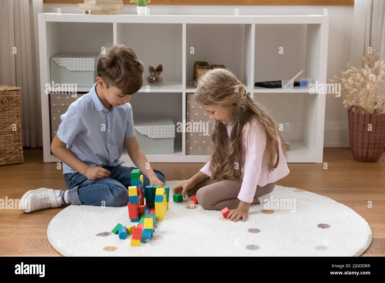 Two little sibling kids constructing house model together Stock Photo