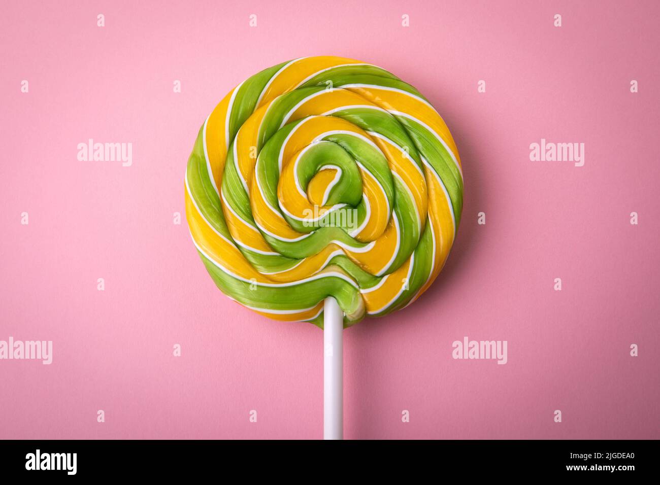 Round spiral candy on a stick. Pink background Stock Photo Alamy