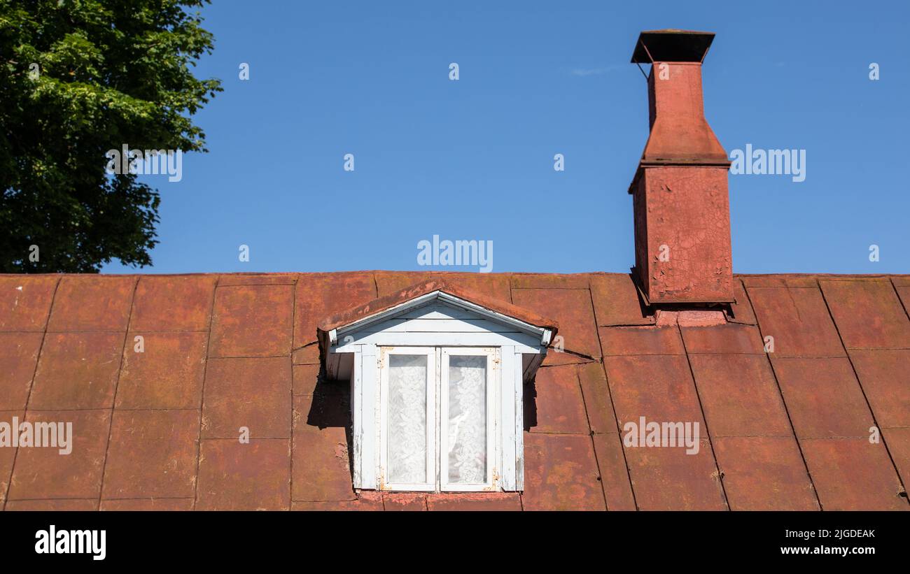 Roof of an old house with a roof window and a chimney. Historical look... Stock Photo