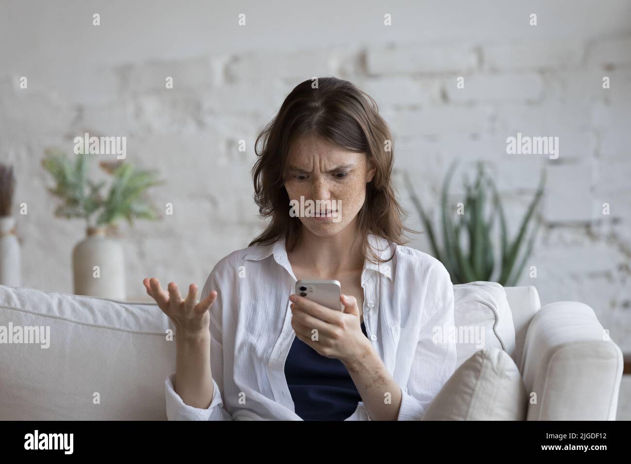 Young woman feels annoyed having problems with broken smartphone Stock Photo