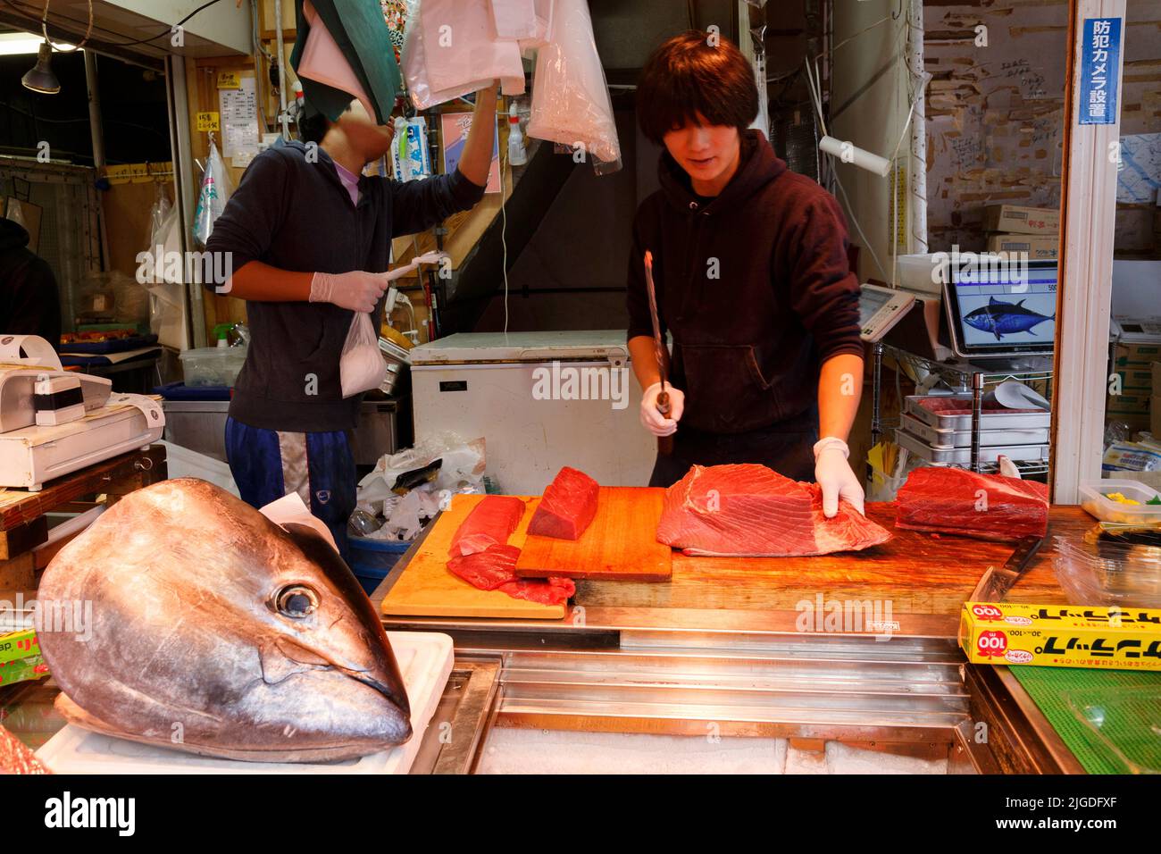 Tsukiji, Tokyo, Japan - June 30, 2022 : Japanese fishmonger slicing yellow fin tuna to sell in the stall at Tsukiji Fish Market in Tokyo, Japan. Selec Stock Photo