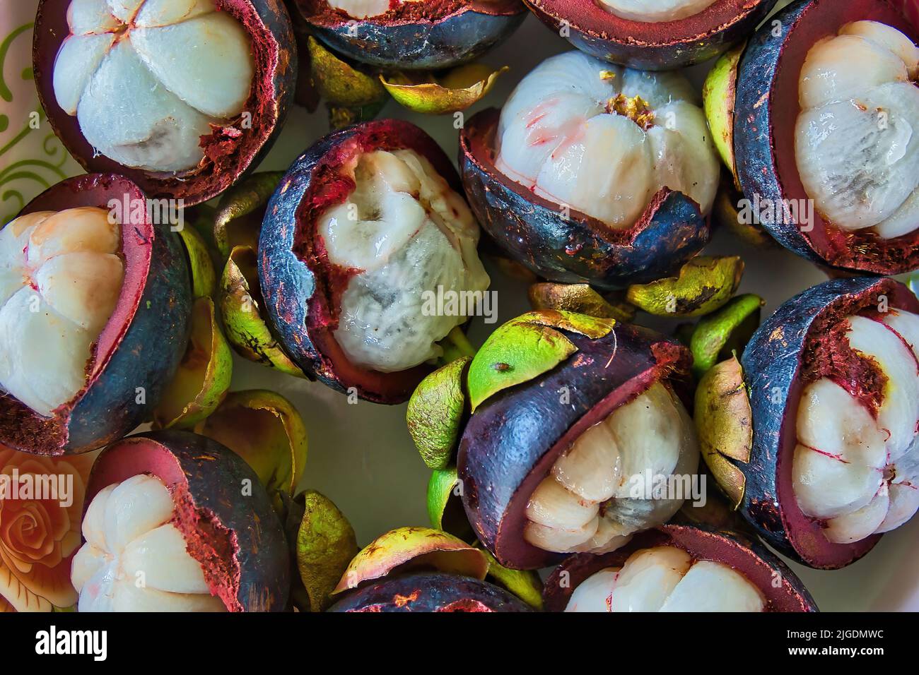 Closeup of tropical mangosteen fruits and cross section of purple skin and white seeds Stock Photo