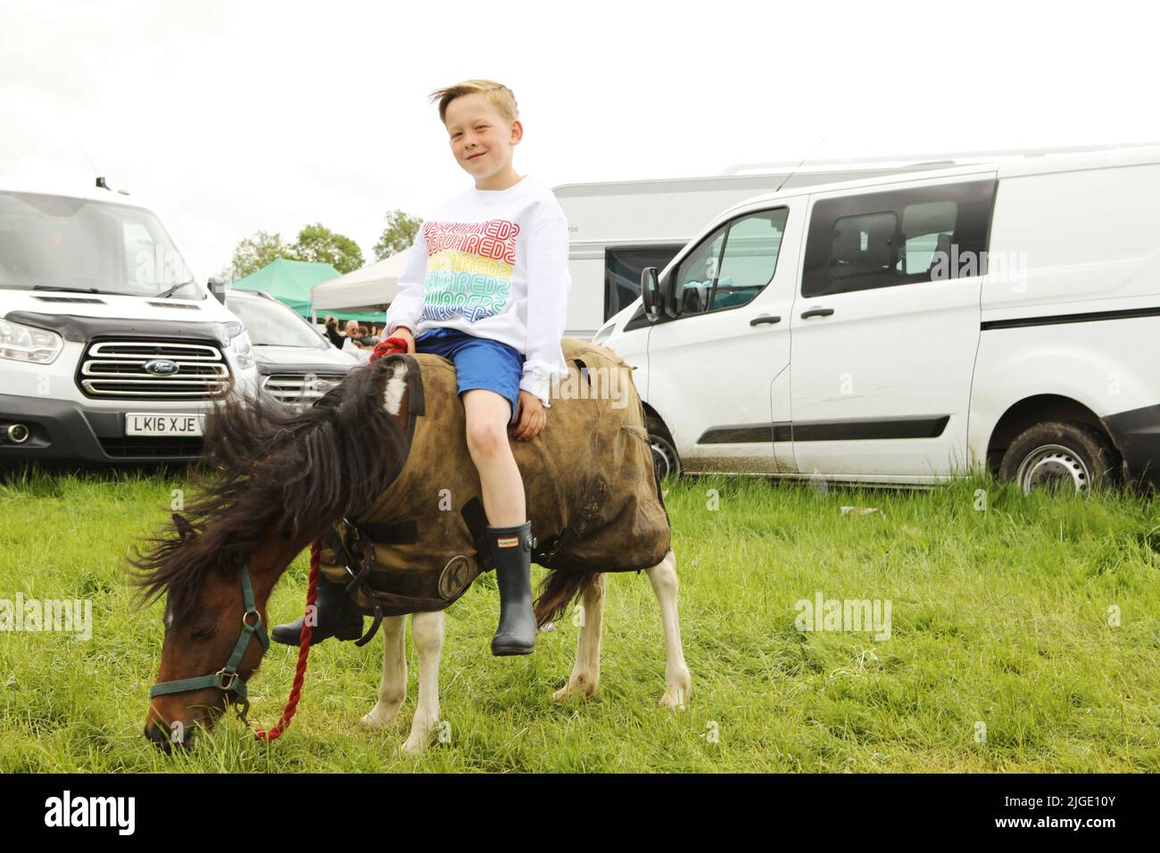 A young boy sitting on a miniature horse. Appleby Horse Fair, Appleby in Westmorland, Cumbria Stock Photo