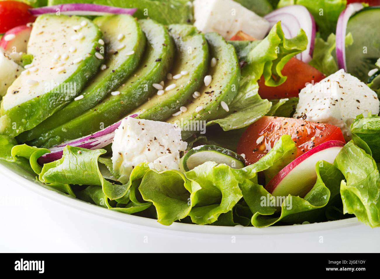 Healthy green salad with avocado feta cheese and fresh vegetables close up Stock Photo