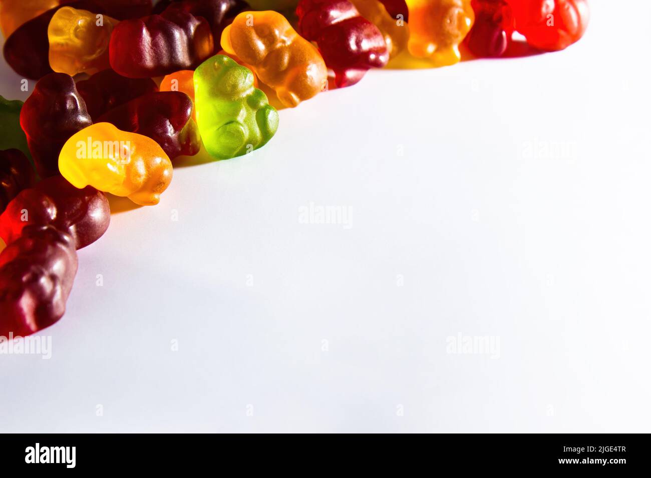 Gummy animals of different colors with fruit juice lie in the upper left corner of the frame on a white background Stock Photo