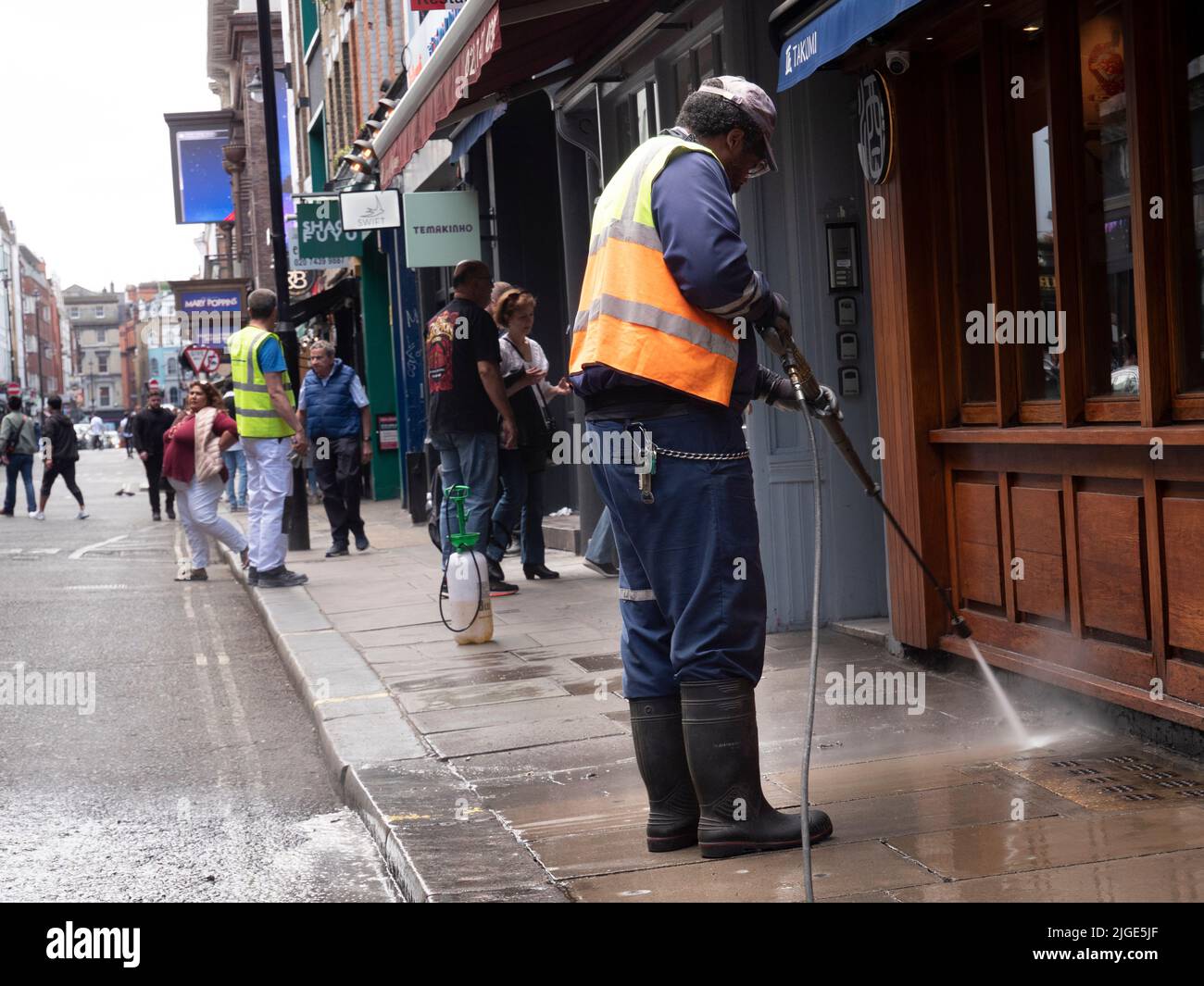 Veolia street cleaner, cleaning pavement in   Soho London, with pressure washer or  jet wash Stock Photo