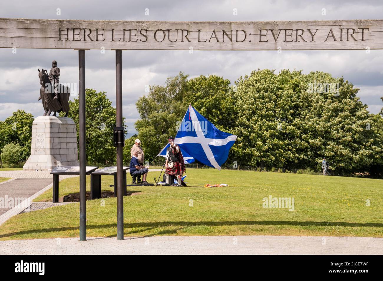 Person with large Scottish flag at Scottish Independence Rally next to statue of Robert the Bruce at Bannockburn, Stirling. Stock Photo