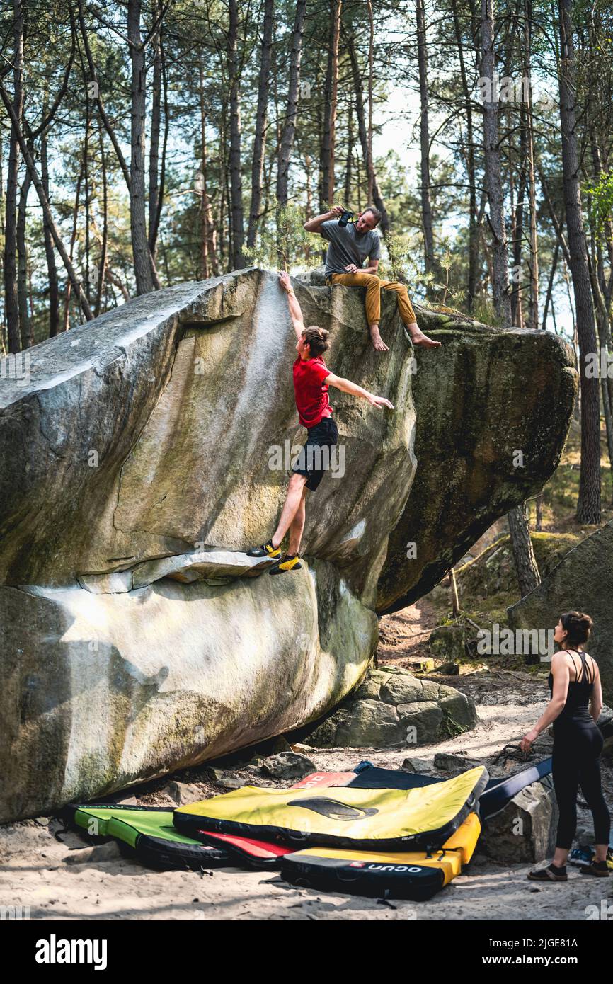 Athletic young man is jumping for top hold in famous and hard dyno boulder problem called 'Rainbow Rocket - 8a'. Fontainbleau, France, Europe. Stock Photo