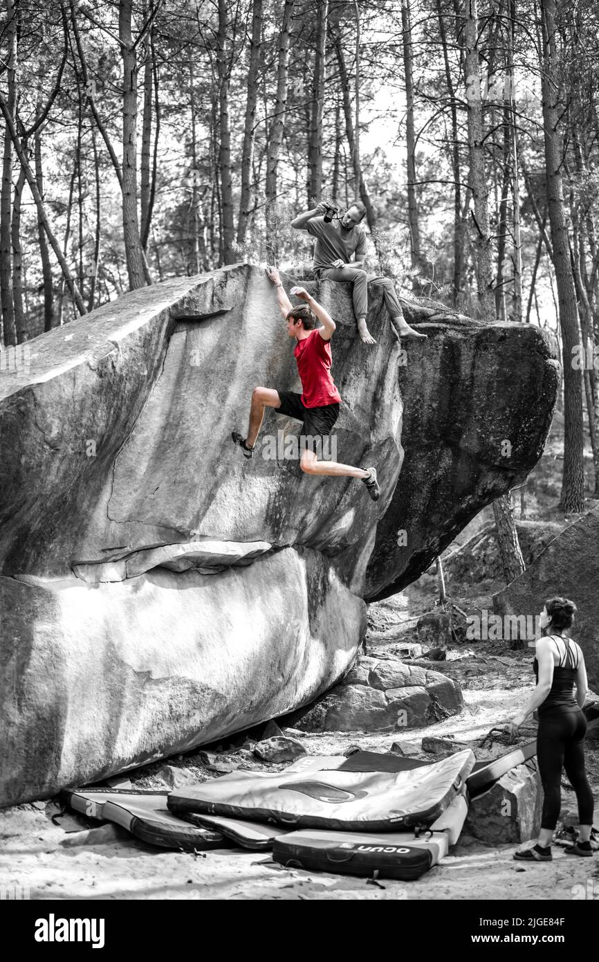 Athletic young man is jumping for top hold in famous and hard dyno boulder problem called 'Rainbow Rocket - 8a'. Fontainbleau, France, Europe. Stock Photo