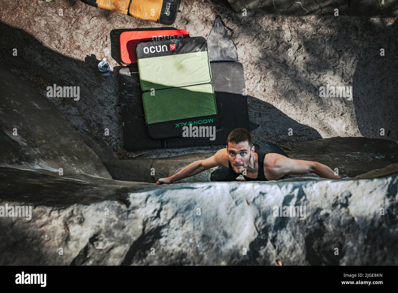 Climber jumps to top hold of dynamic jump boulder. Stock Photo