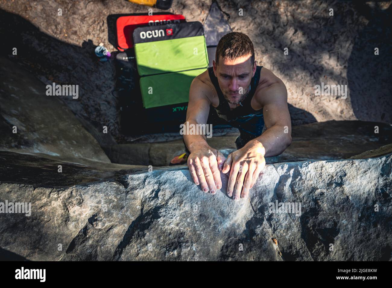 Climber jumps to top hold of dynamic jump boulder. Stock Photo