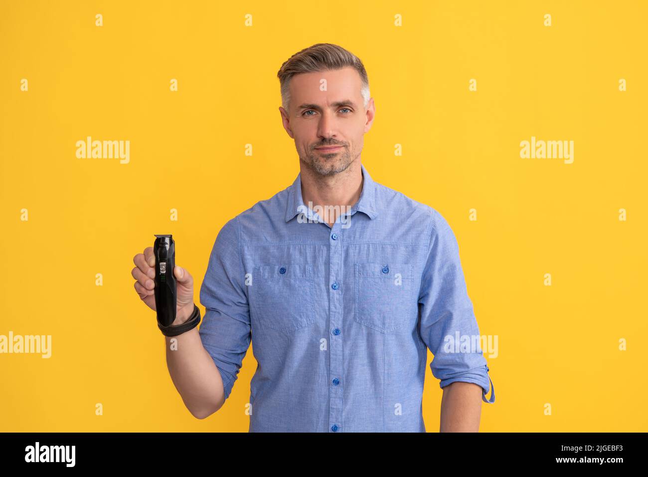 man hold electric razor on yellow background, shaving Stock Photo Alamy