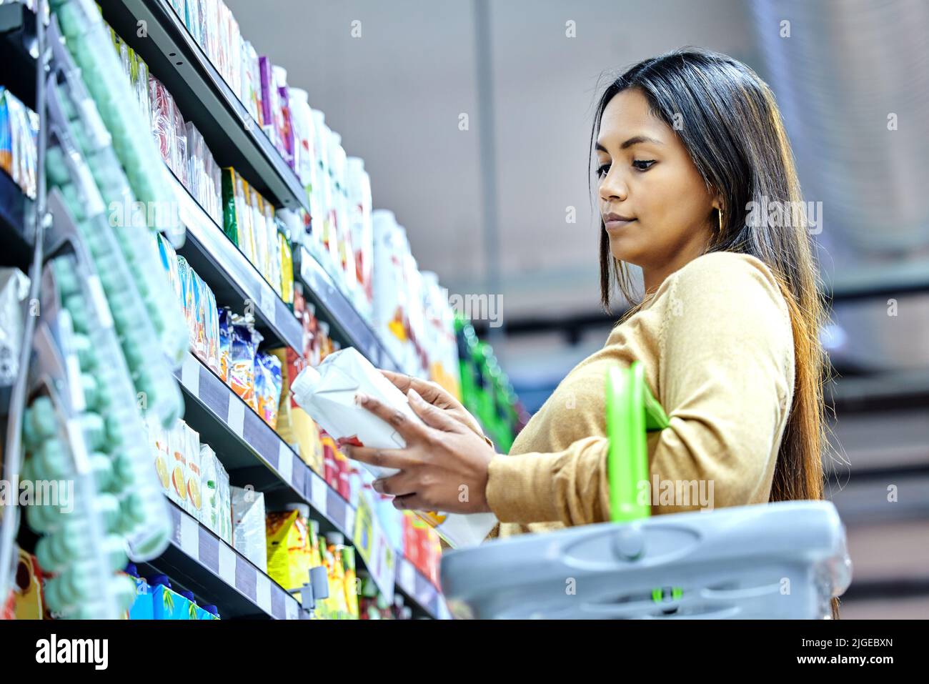 To buy or not to buy a young woman shopping at a grocery store stock