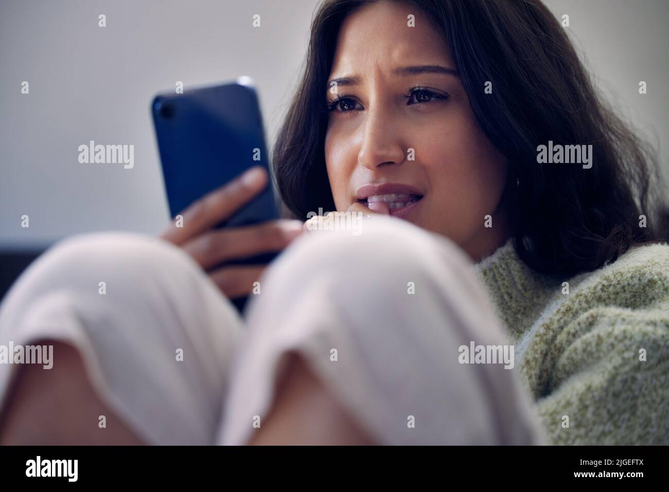 Help is a hello away. a young woman using a smartphone and looking ...