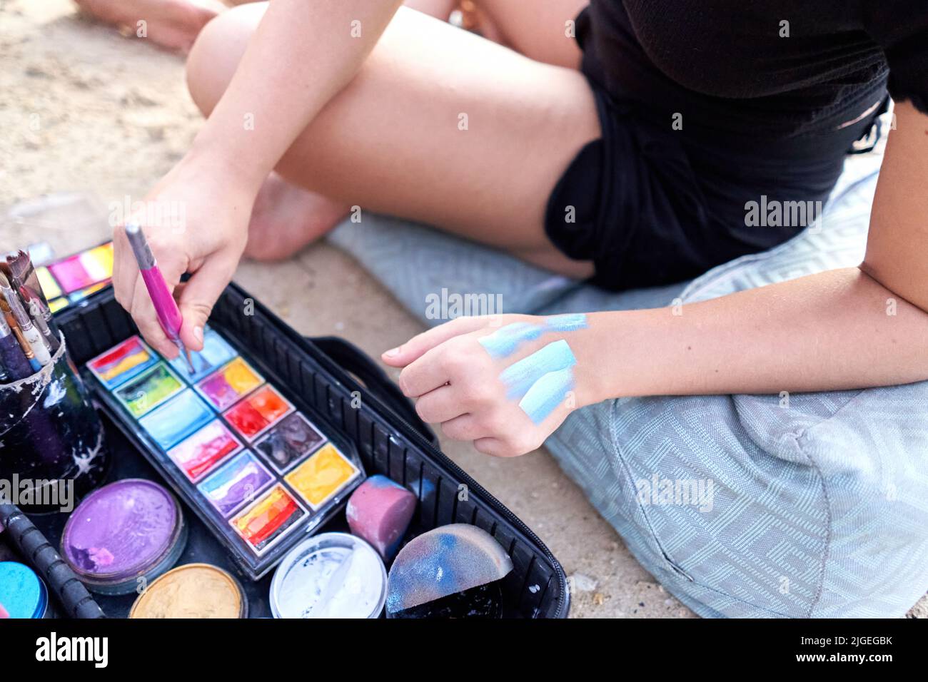 Artist trying out shades of color on her skin during a body paint session. Stock Photo