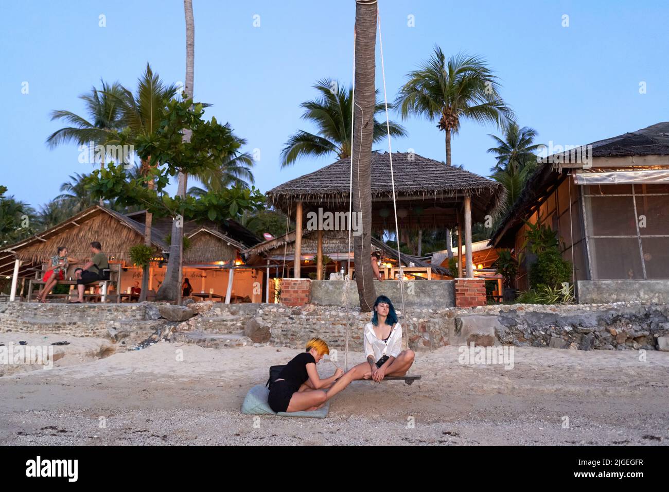 Two woman sitting on the beach during a body paint session Stock Photo