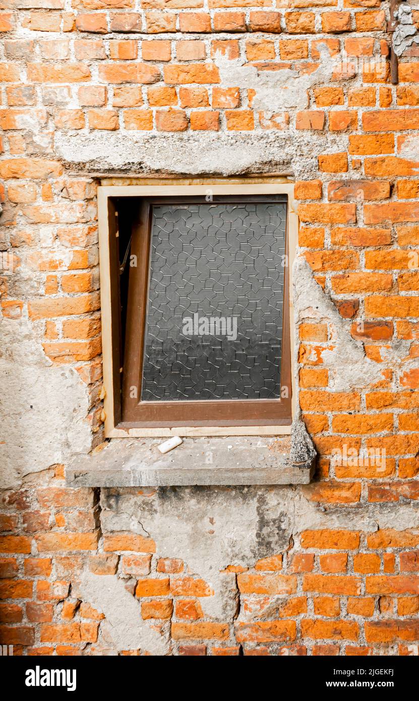 Dirty window in the inner brick wall of a building with messy appearance. Concept - album cover Stock Photo