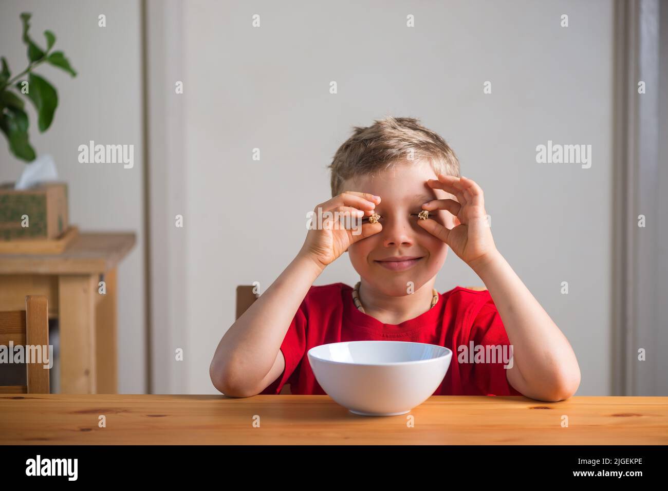 Cute boy playing with granola at breakfast. Genuine expressions Stock