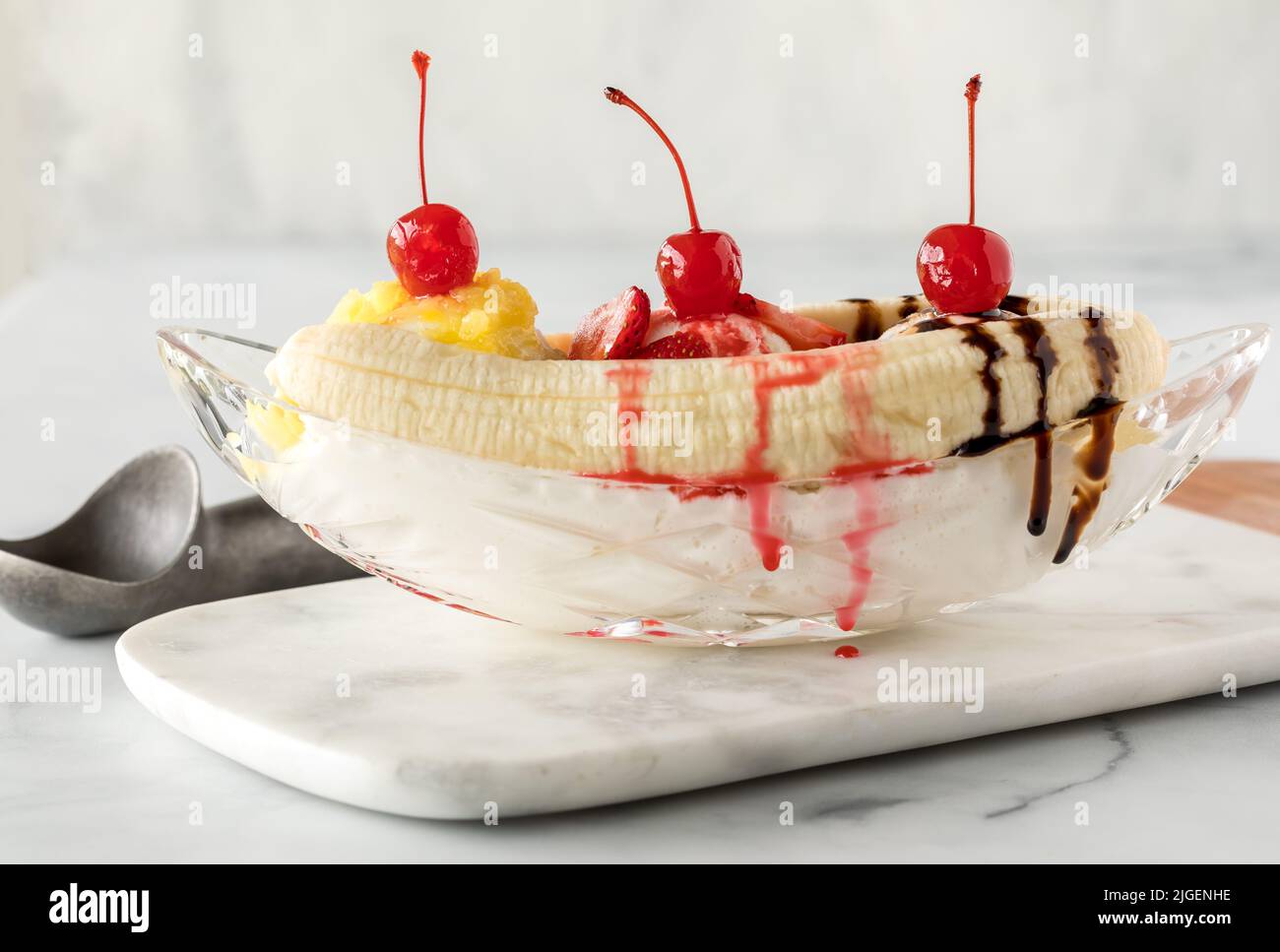 Creamy and delicious banana split on a marble slab, ready for eating. Stock Photo