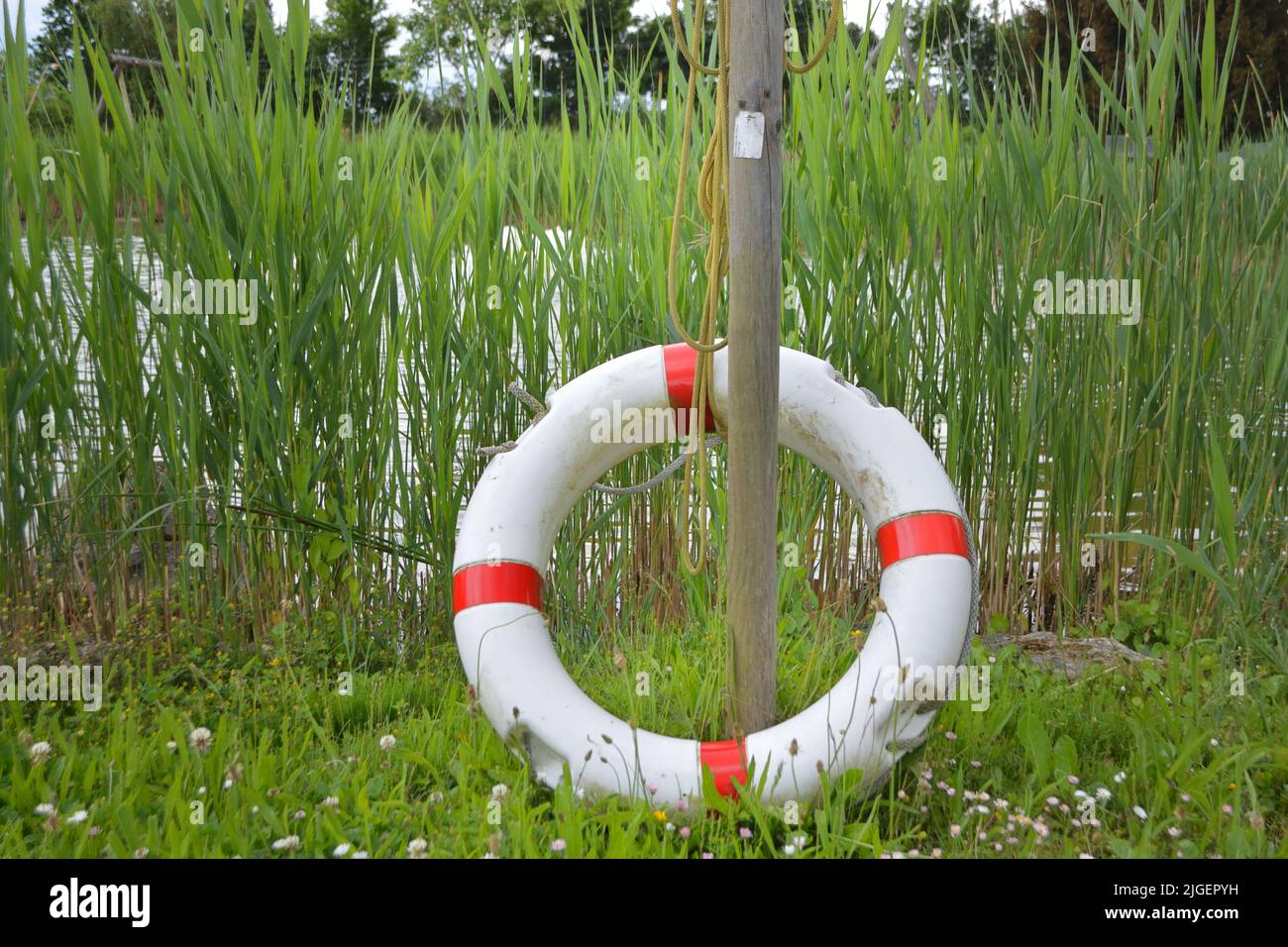 Life saver ring standing next to a lake on a sunny day Stock Photo