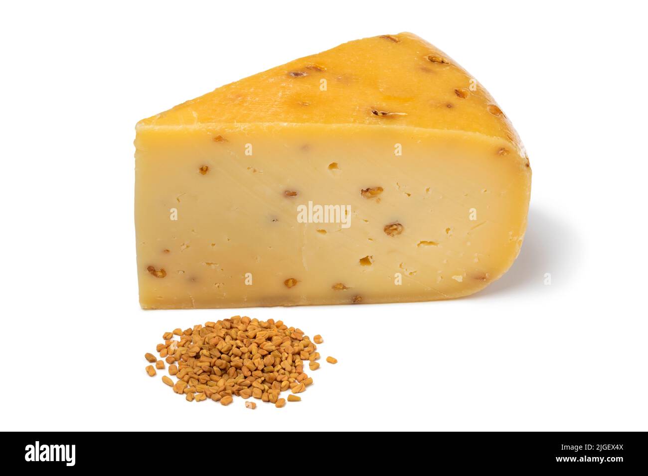 Piece of Gouda cheese with  Fenugreek and a heap of seeds in front  isolated on white background close up Stock Photo