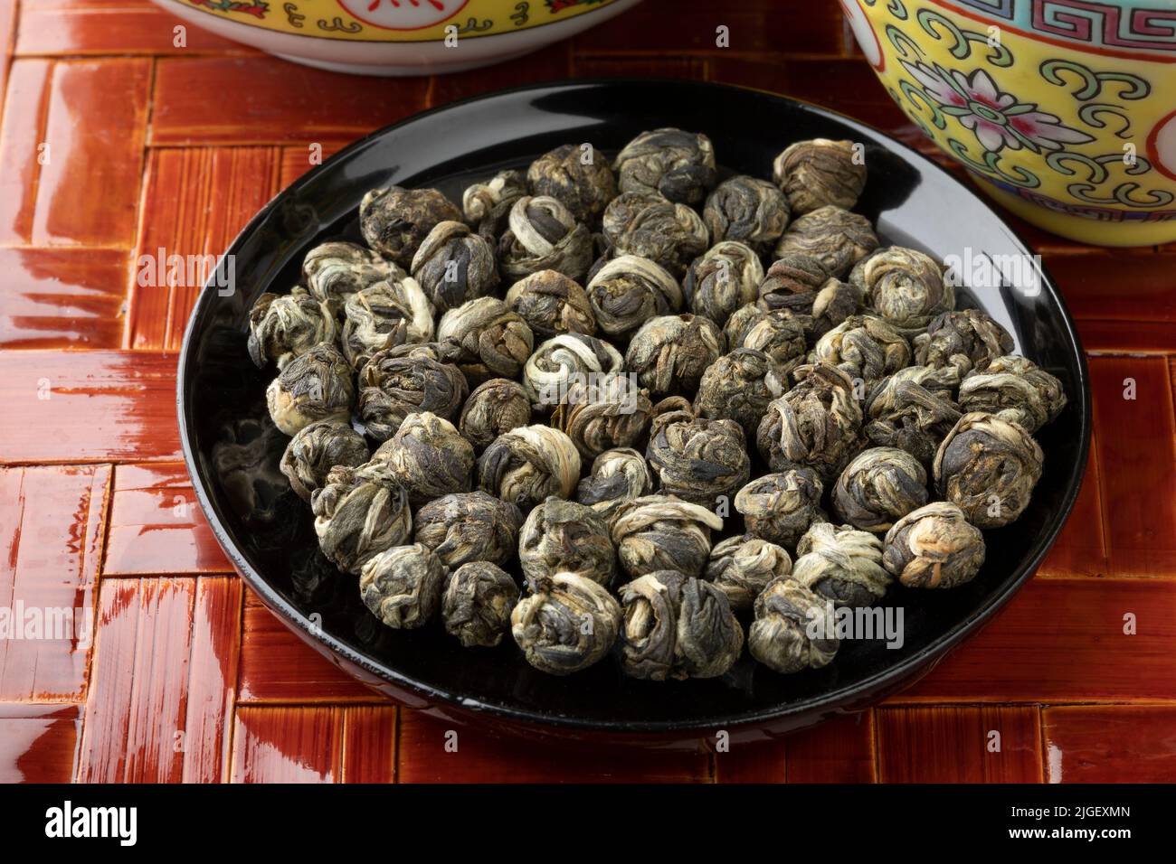Dried Chinese Jasmine Dragon pearl tea leaves on a black bowl close up