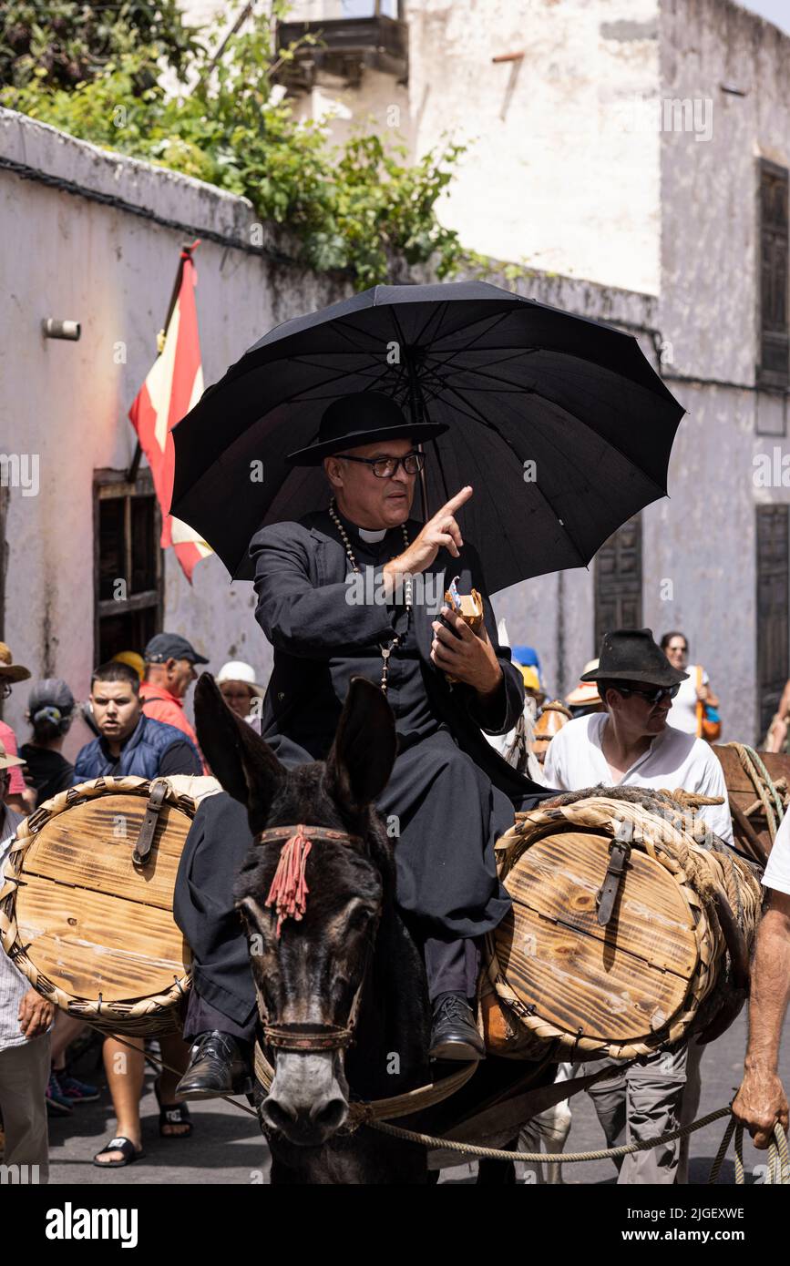 Chirche, Tenerife, 10 July 2022. The priest on the back of a mule blesses people as he passes by. Villagers celebrate the Día de tradiciones, Day of Traditions in the small mountain village where they renact scenes from the rural lifestyle lived by their ancestors in the 1940s Stock Photo