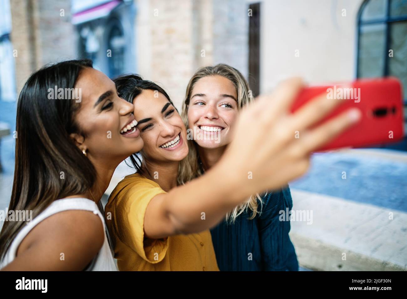 Young happy woman friends of different ethnicities having fun taking selfie Stock Photo