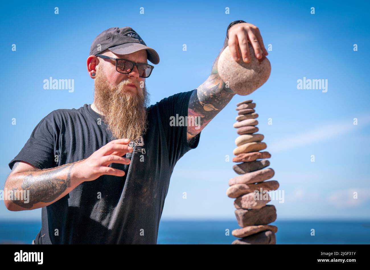 Competitor Aaron Tierney from Falkirk takes part in the 'most stones balanced in 20 minutes' event during the European Stone Stacking Championships 2022 on Eye Cave Beach in Dunbar, East Lothian. The championships are Europe's largest competition for all stone stacking and rock balancing enthusiasts and artists. Picture date: Sunday July 10, 2022. Stock Photo