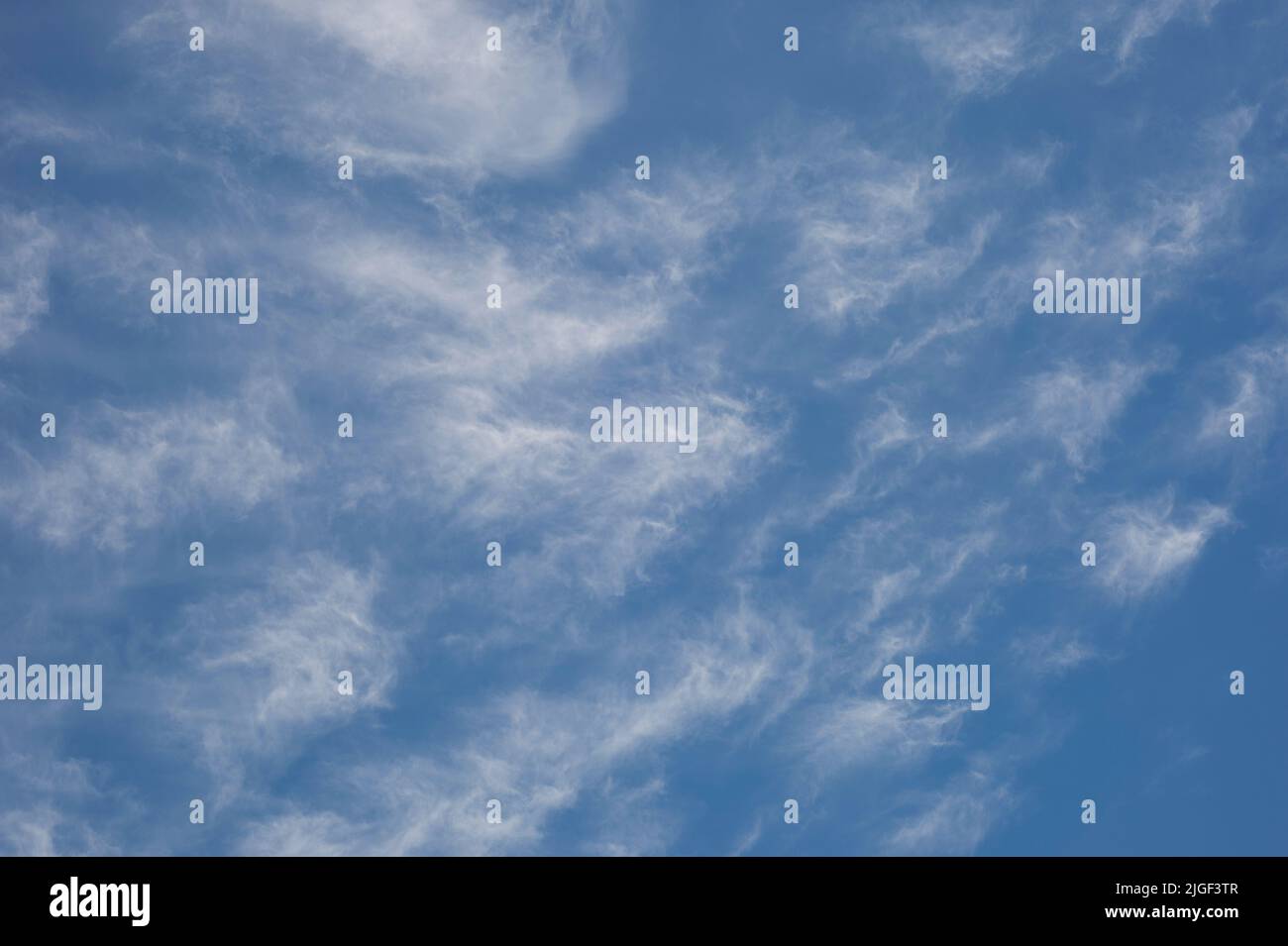 A bright blue sky with white wispy clouds Stock Photo