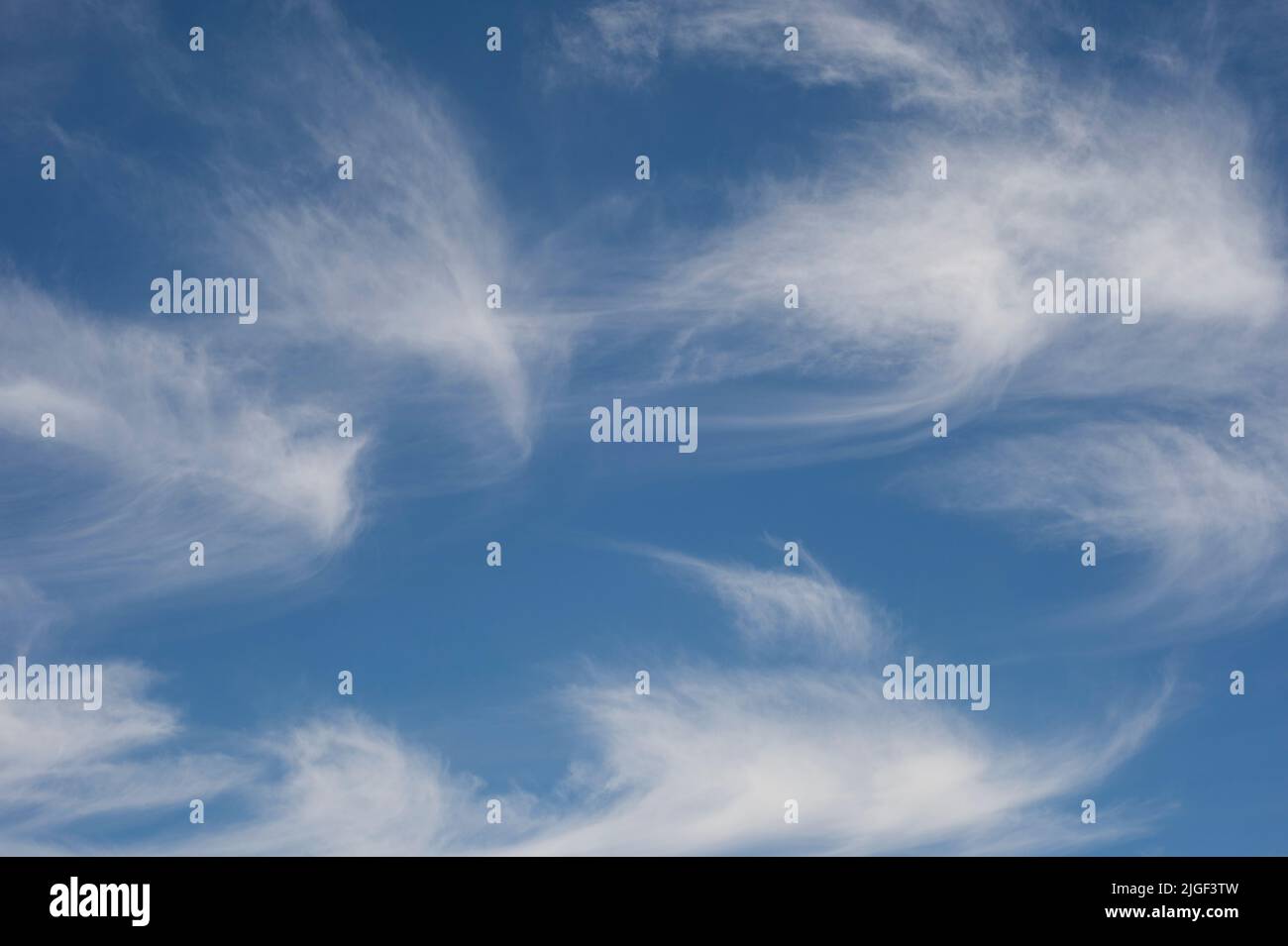 A bright blue sky with white wispy clouds Stock Photo