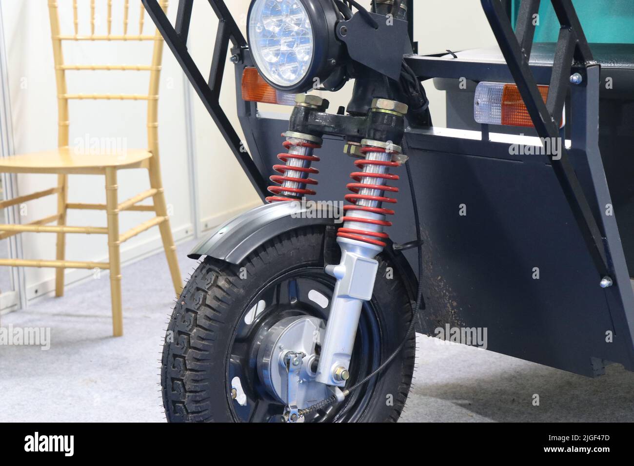 Front part of an electric tricycle with suspension springs and headlights view. Electric auto rickshaw or tuk tuk under manufacturing process Stock Photo