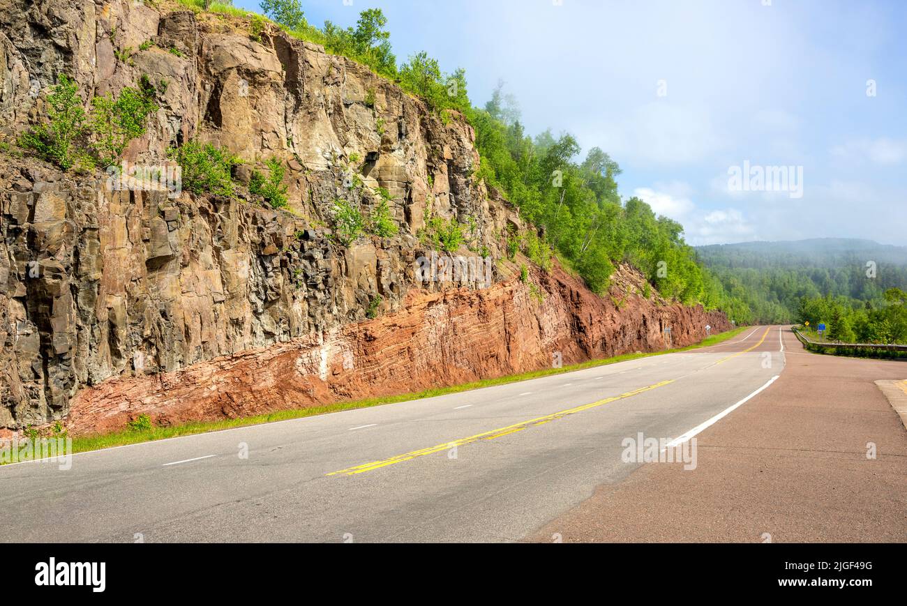 Cross-section of an excavated mountain and rock showing volcanic layers along the North Shore of Lake Superior at Good Harbor Bay, Minnesota Stock Photo